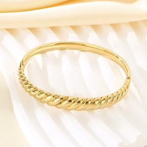 Detailed macro of gold-plated twisted rope texture on wave bangle for women