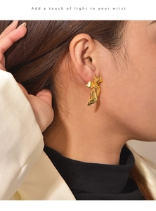 Close-up of a model wearing a gold brass flower earring with a unique textured concave design
