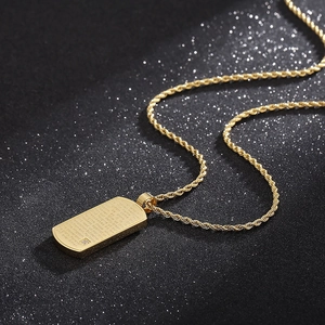 Détail du pendentif rectangulaire en acier doré avec gravure et petite pierre brillante