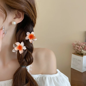 Detail of sweet gradient sunflower hair claw clip worn on a side braid hairstyle