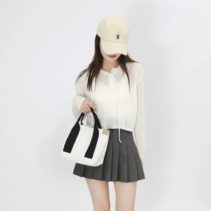 Japanese style white canvas tote bag with black straps held by model in minimalist studio
