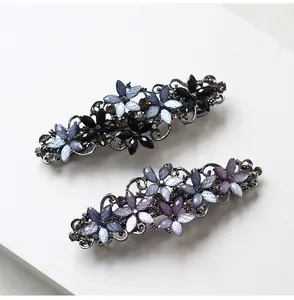 Detailed macro of vintage flower hair clips with dark rhinestones and fine glitter petals