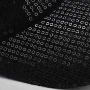 Gros plan de paillettes noires scintillantes sur la maille de la casquette tendance