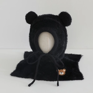 Detail of plush black bear ear hat with soft fur texture and brown teddy bear embroidery