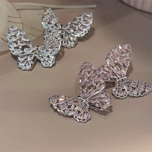 Macro detail of silver needle butterfly earrings featuring colorful cubic zirconia stones