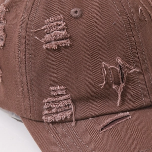 Close-up of brown washed cotton baseball cap featuring vintage distressed ripped details