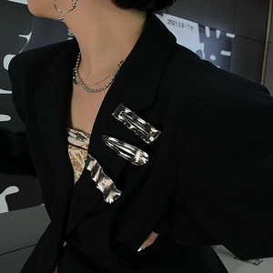 Silver metal hair clip and layered necklace styled on a black blazer lapel for a modern look