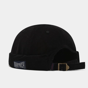 Detail of black corduroy docker hat featuring brand side label and adjustable metal buckle