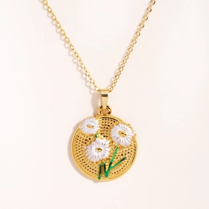 Gros plan du pendentif doré avec trois marguerites blanches sur une texture grillagée