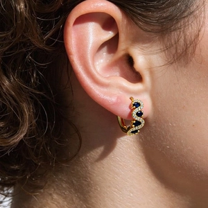 Close-up of wavy gold ear cuff with inlaid blue stones and white crystals on ear