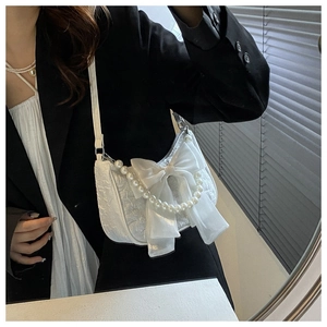 White shoulder bag featuring an oversized organza bow and elegant pearl chain detail