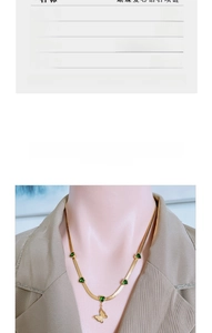 Close-up of gold butterfly necklace with green heart gem on flat blade chain for women