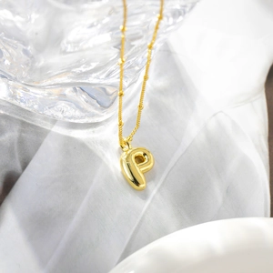 Macro di un ciondolo a lettera P in oro 18K con una catena a sfere lucida