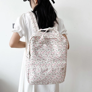 Rear view of model wearing a floral canvas backpack with pink flowers on white fabric