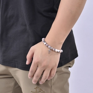 Pink zebra stone bracelet with silver cross pendant on wrist for casual fashion