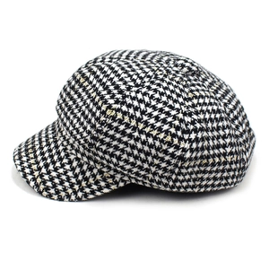 Detail of tweed newsboy cap with black and white houndstooth pattern and golden metallic thread