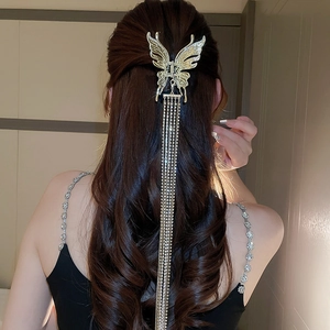 Détail d'une pince à cheveux papillon dorée avec de longs glands en strass brillants