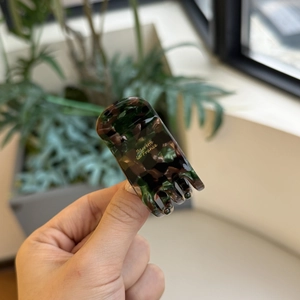 Detail view of the dark tortoiseshell acetate hair claw clip with golden lettering