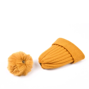 Detail of ginger yellow knit beanie featuring a detachable faux fur pom-pom with snap