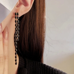 Close-up of elegant gold long drop earrings with faceted black geometric gemstones