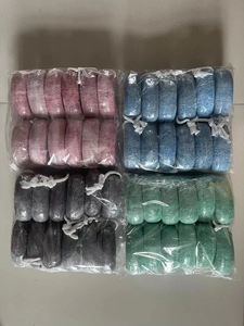 Detailed view of four packs of natural volcanic pumice stones in pink, blue, black, and green