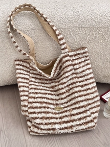 Brown and beige striped faux shearling tote bag with a spacious interior on a cozy sofa