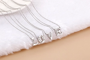 Macro shot of silver stainless steel necklaces with crystal LOVE letter pendants