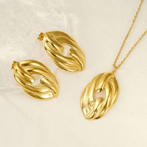 Detail of gold oval jewelry set with textured woven pattern on beige fabric background