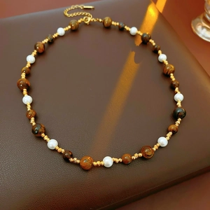 Detail of vintage necklace with brown tiger eye beads and white pearls on leather