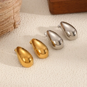 Polished gold and silver stainless steel teardrop earrings on a minimalist wooden display