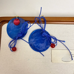 Macro view of blue shell tassel earrings on a wooden jewelry box tray display