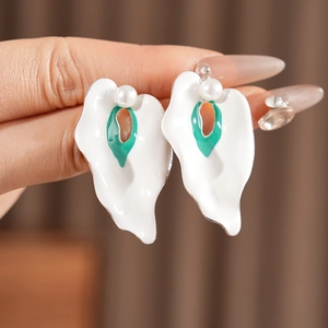 Close-up of vintage enamel petal earrings with green oval center and white pearl detail