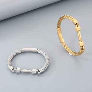 Detail of matte woven steel cable bracelet with barbell charm in silver and gold