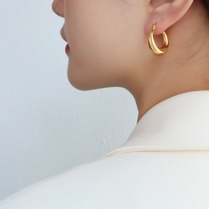 Boucles d'oreilles créoles C en acier inoxydable doré 18 carats sur le mannequin