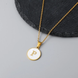 Detail of round shell pendant with gold letter P on a black stone display pedestal