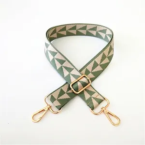 Detail of green and beige geometric woven strap with gold metal swivel hooks