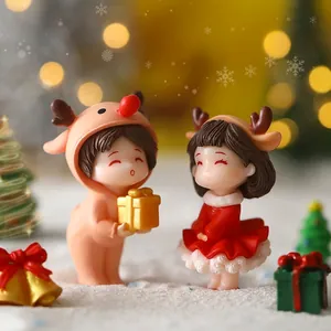 Miniature Christmas couple figurines featuring a boy in a deer suit and girl in a red dress