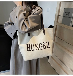 Detailed close-up of a large canvas tote bag with brown leather handles in a home setting