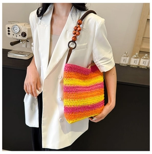 Detail of colorful rainbow woven straw bucket bag with wooden bead handle on model