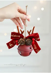 Detail of red Christmas bell ornament with reindeer antlers, pine cones and berries