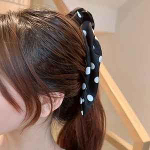 Close-up of elegant black and white polka dot hair claw clip worn on a side ponytail