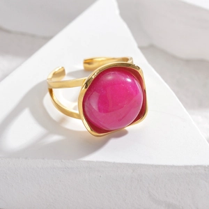 Detail of gold open ring with large fuchsia oval stone on a geometric stand
