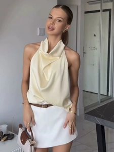 Haut licou élégant en satin beige et jupe blanche portés par un mannequin en studio
