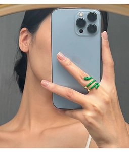 Detail of a green enamel snake ring in gold plating worn on a finger