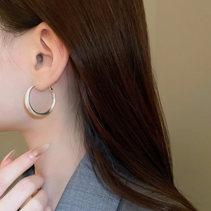 Silver-plated large C-shape hoop earring worn by a model showing matte metal texture