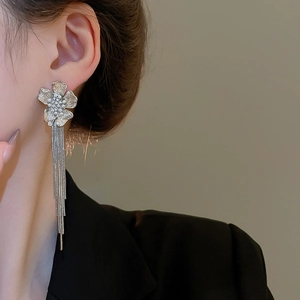 Close-up of elegant floral silver earrings with long fringe tassels worn by a model