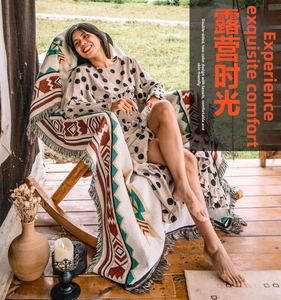 Detail of bohemian geometric blanket with colorful long fringe on a wooden rocking chair