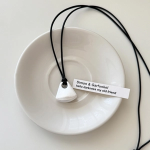 Detailed view of frosted trapezoid pendant with black cord on white ceramic dish