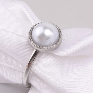 Macro shot of 10mm white round pearl ring with silver polished metal on silk