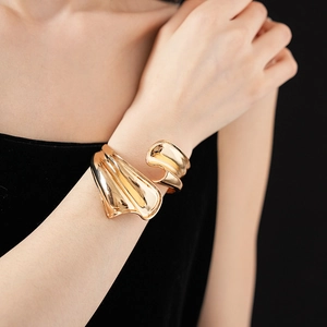 Detailed close-up of a chunky irregular twisted gold cuff bracelet on a model's wrist